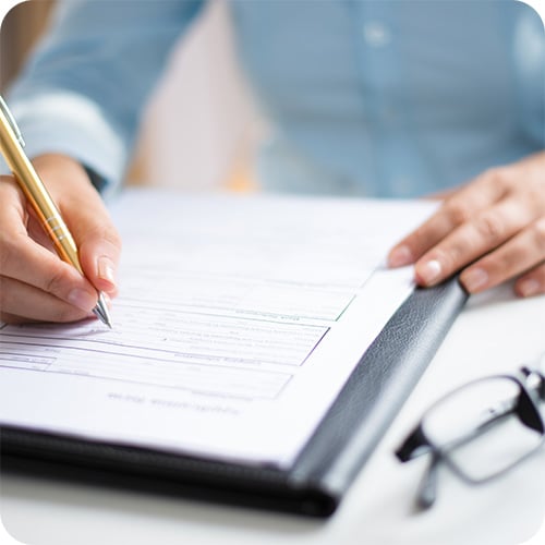 Perusing a legal document with pen and glasses.