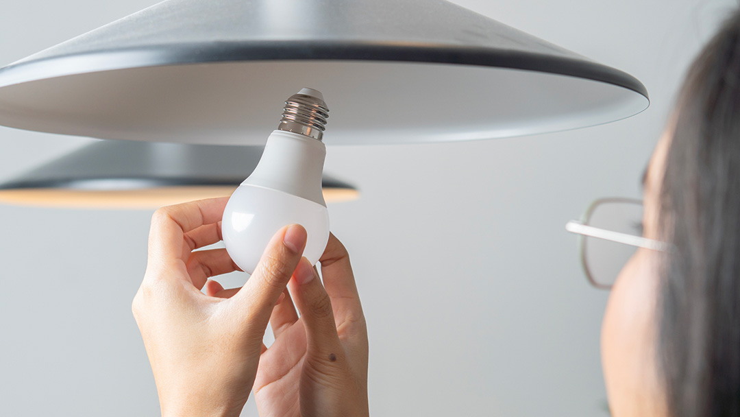 Woman fitting energy-efficient lightbulb