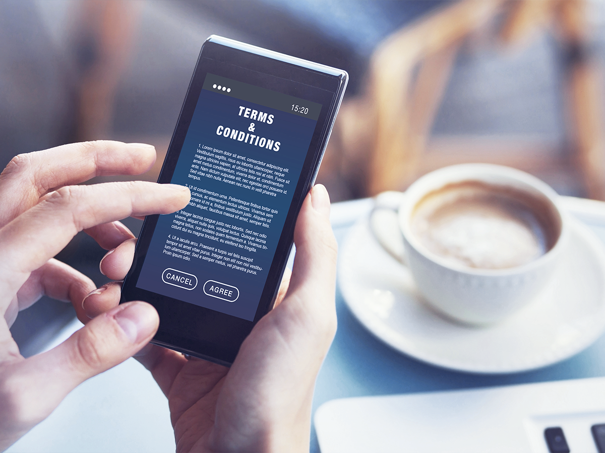 Person reading terms and conditions in their phone in a cafe.