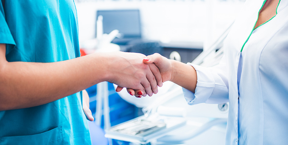 Dentists shaking hands in front of medical equipment