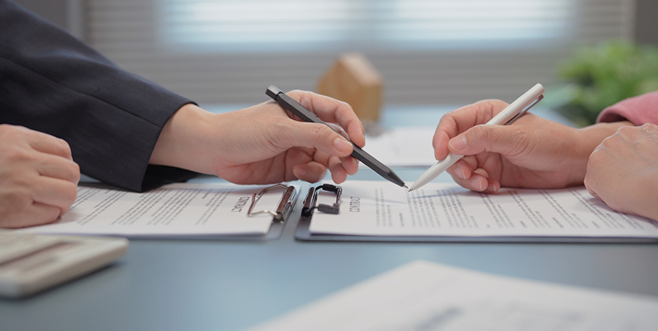 Two hands with pens going over finer details of contract