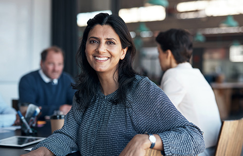 Woman smiling at camera in a cafe whilst doing business