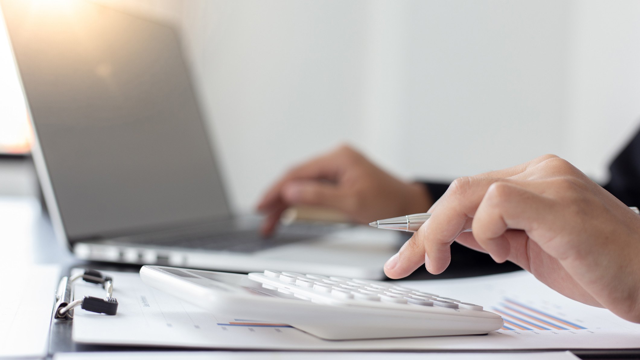 Close-up of person using laptop and calculator
